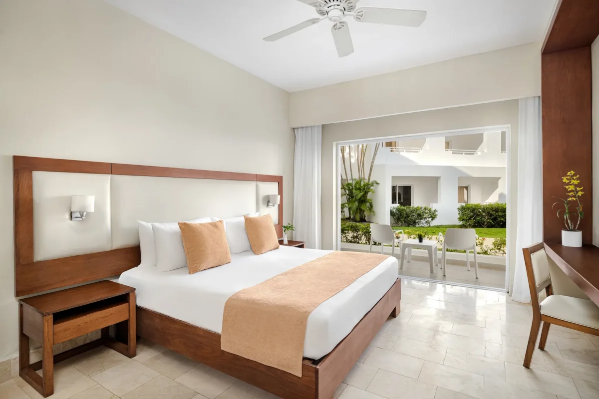 Sun Club Junior Suite Tropical View with king bed and private terrace at Sunscape Dominicus La Romana overlooking lush resort grounds.